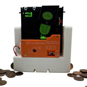 May include: A white 3D-printed CopperCollector stand holding a black and orange JY-800V CPU comparable coin selector. The orange module features text including Model: JY-800V, Precise, Slow, Medium, and Fast. Green QC pass stickers are visible.