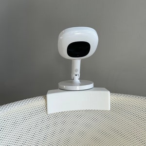 May include: White baby monitor camera mounted on a white mesh bassinet.