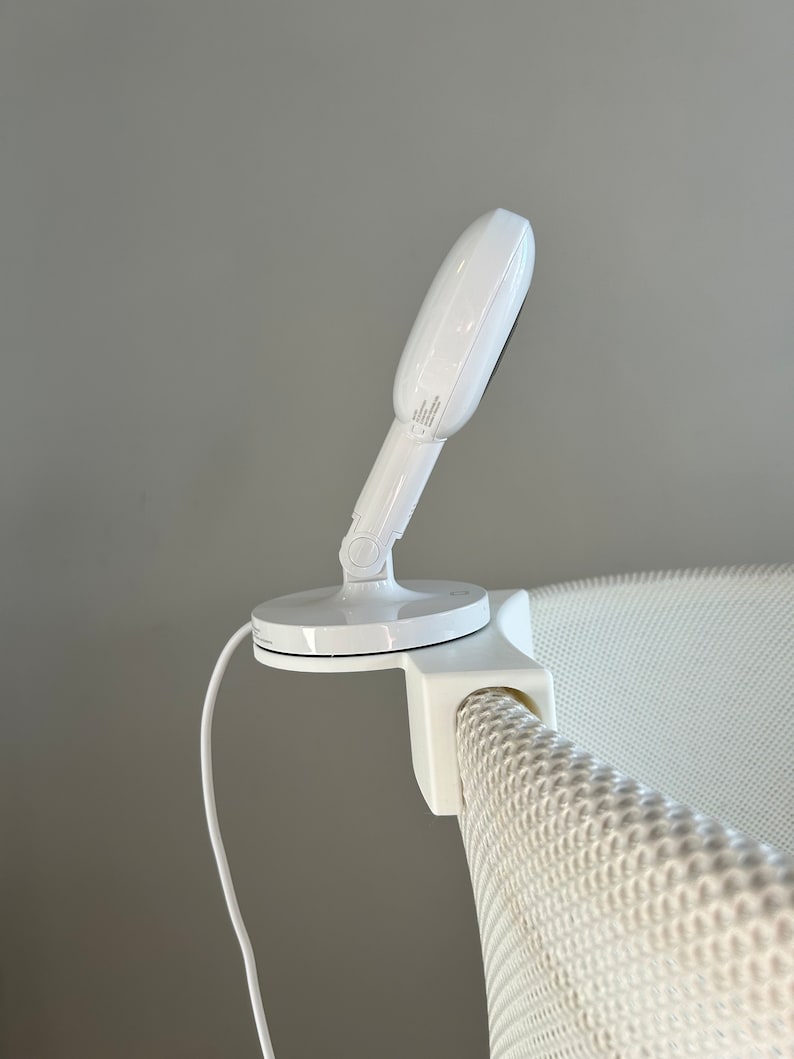 May include: White baby monitor with a round camera lens mounted on a white crib with a mesh side.