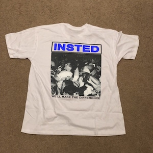 May include: White t-shirt with a black and white photo of a crowd of people. The text "INSTED" is in blue above the photo and the text "WE'LL MAKE THE DIFFERENCE" is below the photo.
