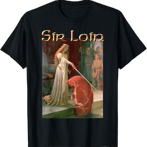 以下が含まれることがあります： 「Sir Loin」という金色の文字が書かれた黒いTシャツ。デザインは、白いドレスを着た女性が大きな肉の塊の上に剣を構えている様子を描いている。