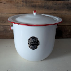 May include: White enamelware pot with a lid and red trim. The pot has a handle on the lid and two side handles. A black and white sticker on the front reads "Durable Porcelain Kanawha Enamel Sanitary."