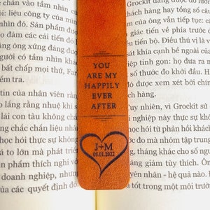 May include: A brown leather bookmark with the text "You are my happily ever after" and a heart with the initials "J+M" and the date "08.01.2022".