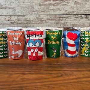 May include: Six colorful, reusable, zippered pouches with different designs featuring characters from the book "The Cat in the Hat". The pouches are labeled with names and the text "3rd Birthday".