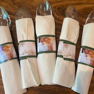May include: Five clear plastic spoons wrapped in white napkins with personalized photo bands. The bands feature a couple's photo and a floral design with green accents.