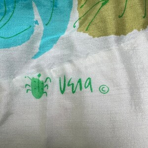 May include: A white fabric with a green bug and the word "Vera" written in green with a copyright symbol.