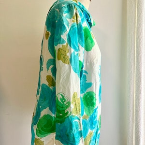 May include: A white blouse with a blue and green floral print. The blouse has a collar and long sleeves.