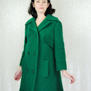 Pu&ograve; includere: Un cappotto di lana verde a doppio petto con colletto e tasche.