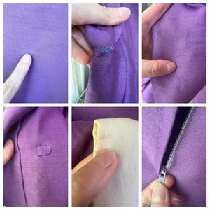 May include: Close-up of a purple zippered sweater with a few small holes. The sweater is made of a soft, stretchy fabric. The zipper is silver and has a small pull tab.
