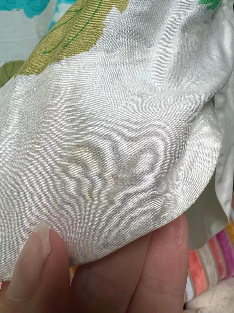 May include: White satin fabric with a light yellow stain. The fabric has a subtle texture and a slight sheen.