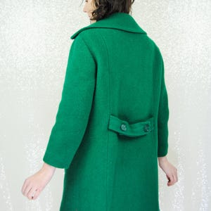 Pu&ograve; includere: Un lungo cappotto di lana verde con chiusura a doppio petto e due bottoni sul retro.