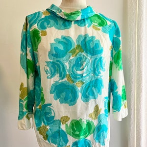 May include: A white blouse with a blue and green floral print. The print features large, abstract roses with a white background.