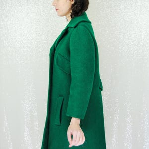 Pu&ograve; includere: Un cappotto lungo verde smeraldo con colletto e tasche. Il cappotto &egrave; realizzato in un tessuto morbido e testurizzato.