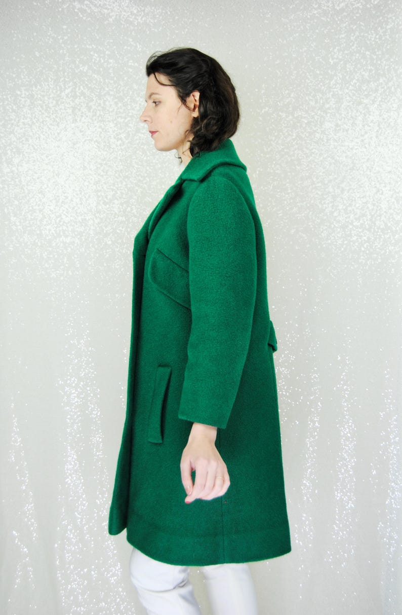 Pu&ograve; includere: Un cappotto lungo verde smeraldo con colletto e tasche. Il cappotto &egrave; realizzato in un tessuto morbido e testurizzato.