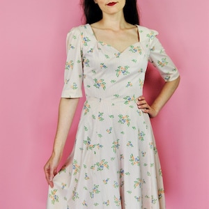 May include: A white dress with a floral print and a sweetheart neckline. The dress has a fitted bodice and a full skirt.
