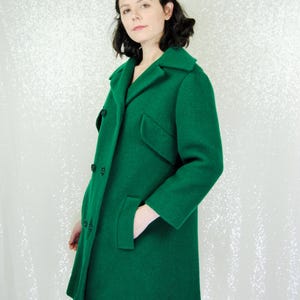 Pu&ograve; includere: Un lungo cappotto verde brillante a doppio petto. Il cappotto ha un colletto classico e due tasche.