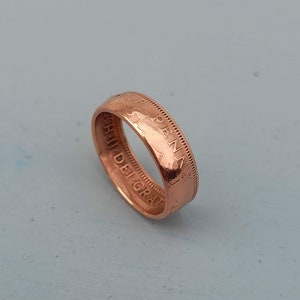 May include: A copper-colored ring made from a penny with the inscription "ONE PENNY" and "THU. DEI. GRA." visible on the side.