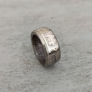 Op de afbeelding: Een zilveren ring gemaakt van een halve kroonmunt. De munt heeft de inscriptie "HALF CROWN" en "REGINA" aan de zijkant.