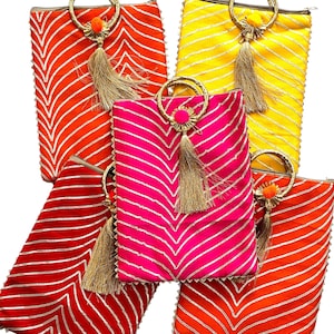 Puede incluir: Cinco bolsos de mano coloridos con asas de anillo dorado y borlas. Los bolsos presentan un patrón en zigzag en tonos de rojo, naranja, rosa y amarillo con rayas metálicas doradas. Cada bolso tiene un pequeño detalle de pompón.