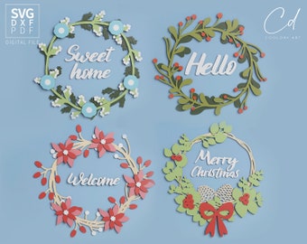 May include: Four paper cut-out wreaths with different greetings. The top left wreath is blue and green with the text "Sweet home". The top right wreath is green with the text "Hello". The bottom left wreath is red and white with the text "Welcome". The bottom right wreath is green and red with the text "Merry Christmas".