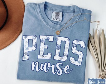 Camisa de enfermera de PEDS con colores cómodos y copos de nieve®, camiseta azul de enfermera pediátrica de invierno, regalo para enfermera titulada, enfermera pediátrica de urgencias, PEDS de Navidad