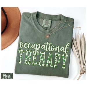May include: Green t-shirt with the text "occupational therapy" in white letters. The letters are outlined with a pattern of green shamrocks.