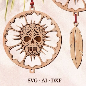 May include: A wooden ornament featuring a sugar skull design with intricate details, surrounded by a flower shape. The ornament is attached to a string and has a feather charm hanging below.