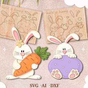 Puede incluir: Dos kits de manualidades de conejos de madera con el texto "build a bunny". Un conejo sostiene una zanahoria, el otro está sentado sobre una base morada en forma de huevo. Los kits incluyen archivos SVG, AI y DXF.