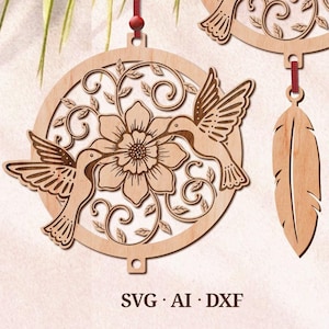 Puede incluir: Adorno de madera con dos colibríes en vuelo, una flor grande y diseños florales intrincados. El adorno está suspendido de una cuerda roja e incluye un amuleto de pluma de madera separado.