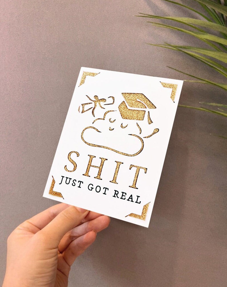 Peut inclure: Carte de graduation dor&eacute;e &agrave; paillettes avec un bonnet de graduation dessin anim&eacute; et le texte "SHIT JUST GOT REAL".