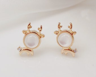 May include: A pair of gold-tone reindeer stud earrings with white pearl-like centers and clear rhinestone accents.