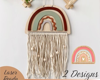 May include: Two laser cut wooden rainbow designs with a fringe and beads hanging from the top. The first rainbow is layered with red, green, and brown, and the second rainbow is layered with pink, green, and brown. The text "2 Designs" is at the bottom of the image, with the file types .SVG, .EPS, .AI, .DXF, .PDF, and .CDR listed below.