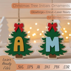 May include: Two wooden Christmas tree ornaments with the letters "A" and "M". The trees are green with a red bow at the top and a light brown base. The letter "A" is yellow, and the letter "M" is light blue. The text "Christmas Tree Initials Ornaments" is at the top.