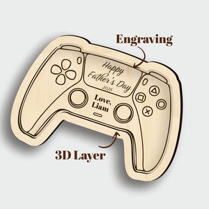 K&ouml;nnte beinhalten: Ein Holztablett in Form eines Gamecontrollers mit 3D-Schicht-Design. Das Tablett ist mit dem Text "Happy Father's Day 2025" und "Love, Liam" graviert. Das Controller-Design umfasst Tasten und ein Steuerkreuz.