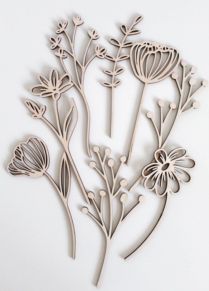 May include: A set of six wooden flower cutouts in a variety of shapes and sizes. The cutouts are all in a natural wood color and have a simple, minimalist design.