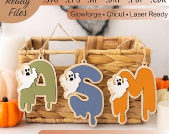 May include: Wooden Halloween alphabet tags spelling out "ASM". Each letter is a different color: green, blue, and orange. Each letter has a white ghost attached. The tags are hanging in front of a wicker basket. The text "Laser Ready Files" is at the top.