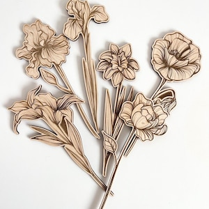 May include: A set of six laser-cut wooden flower shapes, including irises, lilies, and a poppy. The flowers are all in a light brown color and have intricate details.