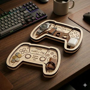 K&ouml;nnte beinhalten: Zwei Holztabletts in Form von Spielecontrollern. Ein Tablett enth&auml;lt eine Uhr, Ringe und einen Schl&uuml;sselanh&auml;nger. Das andere Tablett hat M&uuml;nzen und ein Armband. Auf den Tabletts steht "Happy Father's Day 2025" und "You are The Best Daddy Ever 2025".