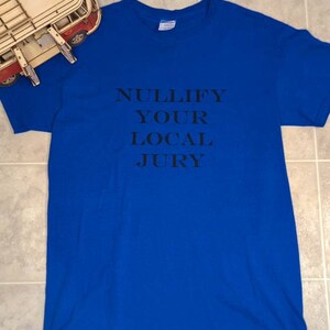 May include: A royal blue t-shirt with the text "NULLIFY YOUR LOCAL JURY" printed in black.