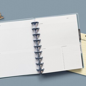 May include: An open planner with a blue cover and black rings. The left page has the word "January" and the right page has the word "February". The pages are blank and have a grid pattern.