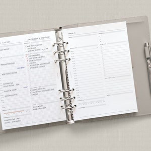 May include: A gray leather bound planner with a silver binder ring system. The planner is open to a daily page with a to-do list and a section for priorities. The page is dated "Today is..." and includes the text "Don't be busy, be productive!"