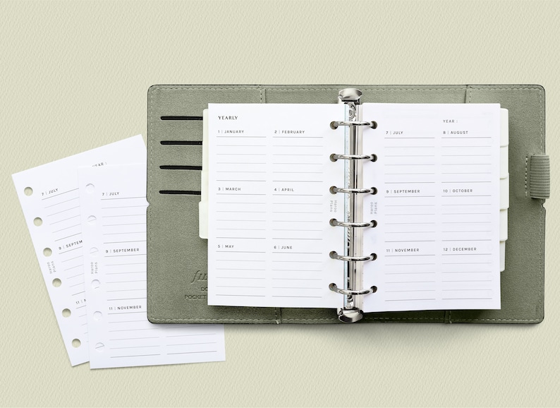 K&ouml;nnte beinhalten: Ein grauer, ledergebundener Taschenplaner mit einem j&auml;hrlichen Kalendereinsatz. Der Kalender ist in 12 Monate unterteilt, mit Zeilen zum Schreiben von Notizen.