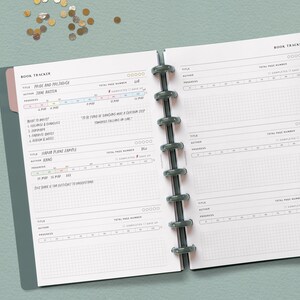 May include: A book tracker with a gray cover and pink tabs. The pages are white with black grid lines and text. The text includes "Book Tracker", "Pride and Prejudice", "Jane Austen", "Total Page Number", "Completed", "Give Up", "Read to Analyze", "To be sure of dancing well was a certain step towards feeling free in life", "Hard Plane Sample", "King", "Madsen", "Total Page Number", "Completed", "Give Up", "This book is the difficult to understand", "Title", "Author", "Progress", "Total Page Number", "Completed", "Give Up", "Title", "Author", "Progress", "Total Page Number", "Completed", "Give Up", "Title", "Author", "Progress", "Total Page Number", "Completed", "Give Up".