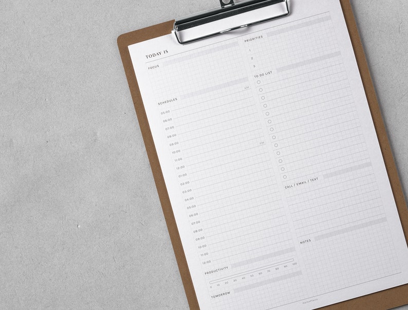 K&ouml;nnte beinhalten: Ein braunes Clipboard mit einem wei&szlig;en Blatt Papier. Das Papier hat ein Tagesplaner-Layout mit Abschnitten f&uuml;r Priorit&auml;ten, To-Do-Liste, Zeitplan, Anrufe/E-Mails/SMS, Notizen und Produktivit&auml;t.
