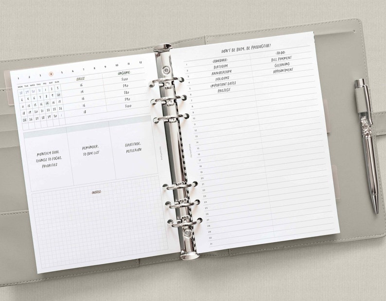 May include: A white planner with a gray cover. The planner is open to a page with a calendar, a to-do list, and a section for notes. The page also includes the text "Don't be busy, be productive!" and a list of items to do.