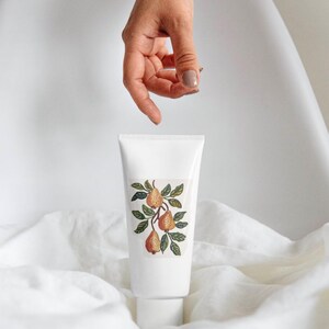 May include: A white tube with a pear illustration. The label features three pears in shades of orange and brown, with green leaves. The tube is on a white surface, with the text "Watercolor Collection" and "Collection by Pati Paints".