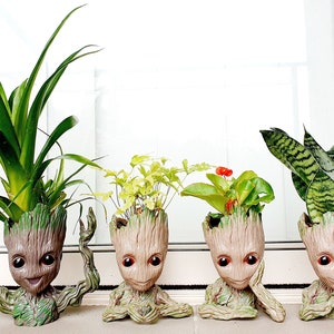 May include: Four potted plants in unique green and brown ceramic planters shaped like the character Groot from the Guardians of the Galaxy movie franchise.