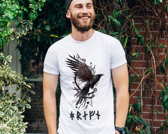 Könnte beinhalten: Weißes T-Shirt mit einem schwarzen Raben-Motiv und dem Text "*R*T*Y*T*" auf der Vorderseite.