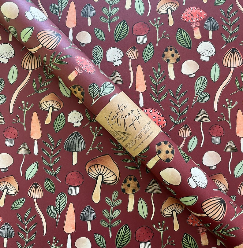 May include: Red and white wrapping paper with a repeating pattern of mushrooms, leaves, and flowers. The paper is rolled up and has a label that says "Kourtni Quinn Art" and "Sheets of Wrapping Paper 20" x 29" per sheet".