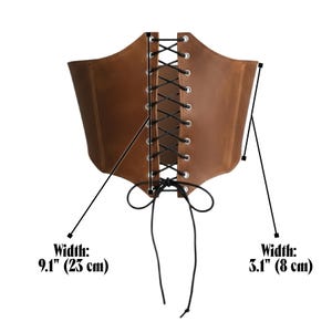 May include: Brown leather corset with black lacing. The corset has a width of 9.1 inches (23 cm) at its widest point and 3.1 inches (8 cm) at its narrowest point. The corset is designed to cinch the waist.